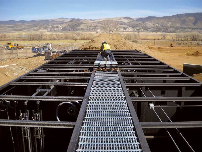 A worker installs walkway grating on an Ashbrook unit